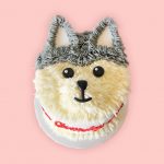A cute cake designed as a fluffy husky face with creamy grey and white fur.