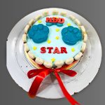 Blue birthday cake with two large paw prints and red ribbon around the base.