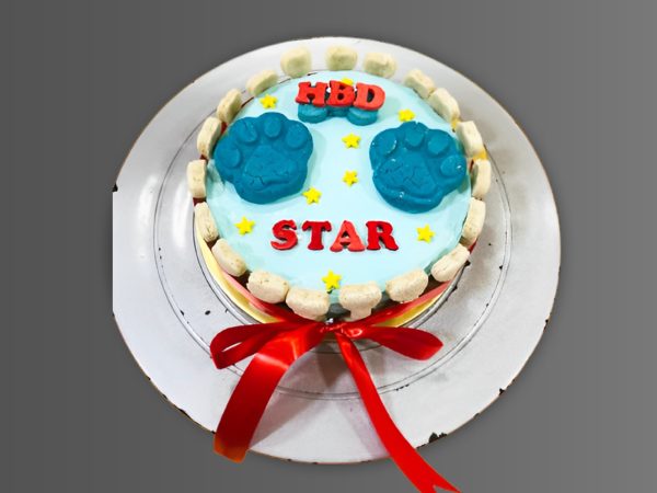 Blue birthday cake with two large paw prints and red ribbon around the base.
