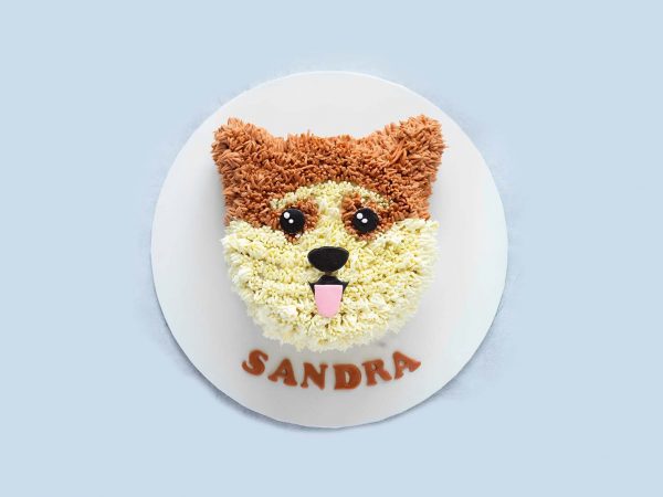 Realistic corgi-shaped dog birthday cake with creamy fur texture and cute eyes, placed on a white base.