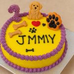 Yellow round birthday dog cake with toy decorations