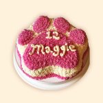 aw cake with pink frosting and custom message written in cream for dog
