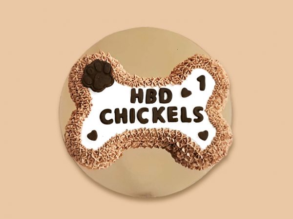 A large bone-shaped dog cake with textured frosting edges and a dark chocolate-like paw print on one end.