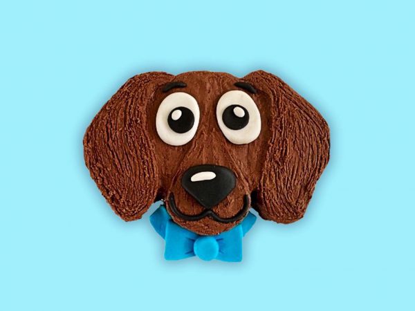 Cute dachshund-themed dog birthday cake comes with a large fondant face with long ears and a blue bow.
