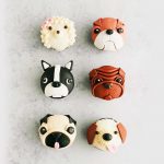 Six cupcakes decorated with dog face designs with various breeds,