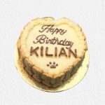 A beige cake with piped cream and biscuit border