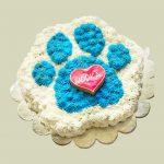 Paw-shaped cake with blue and white frosting, decorated with a red heart-shaped cookie at the center.
