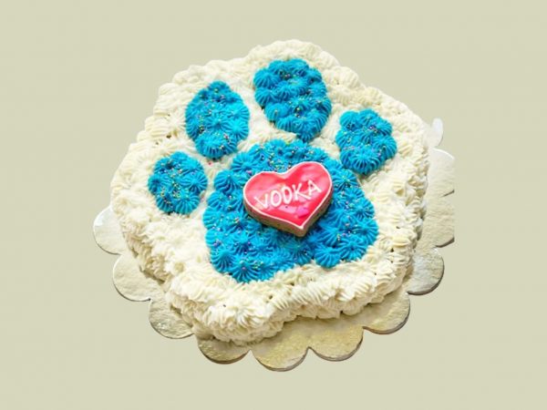 Paw-shaped cake with blue and white frosting, decorated with a red heart-shaped cookie at the center.