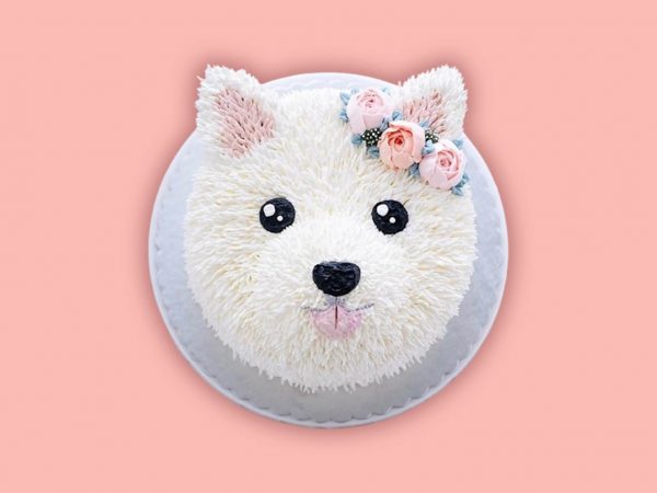 Pomeranian face-shaped cake with white frosting and creamy textures on the head.