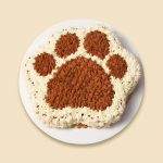 A dog cake designed in a paw shaped cake. With creamy frosting and dog friendly ingredients