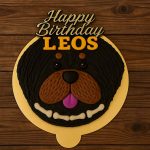 Rottweiler-themed dog face cake with black and brown icing and Happy Birthday topper.