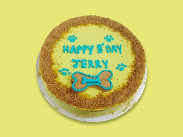 A round yellow frosted dog cake with blue paw print decorations and crumb-coated edges.