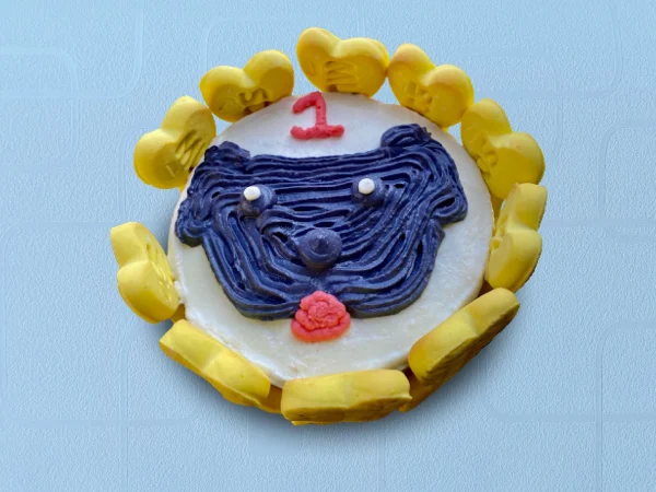 Round cake designed with a simple dog face drawn in icing with a yellow border