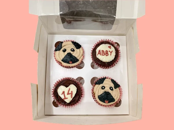 Set of four pug-themed cupcakes in a box, including name and number details in dog-safe ingredients.