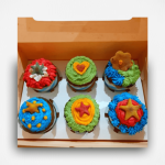 Colorful dog-friendly cupcakes with fresh frosting and star-shaped treats, arranged in a cardboard box.