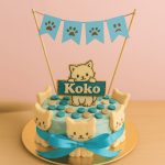 Cat-themed blue cake with "Koko" topper, paw prints, and cat face decorations